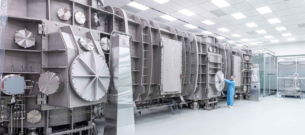 Wide shot of the compressor for generating laser pulses at ELI Beamlines to investigate the feasibility of producing coherent gamma rays. A person in safety gear stands near the instrument.