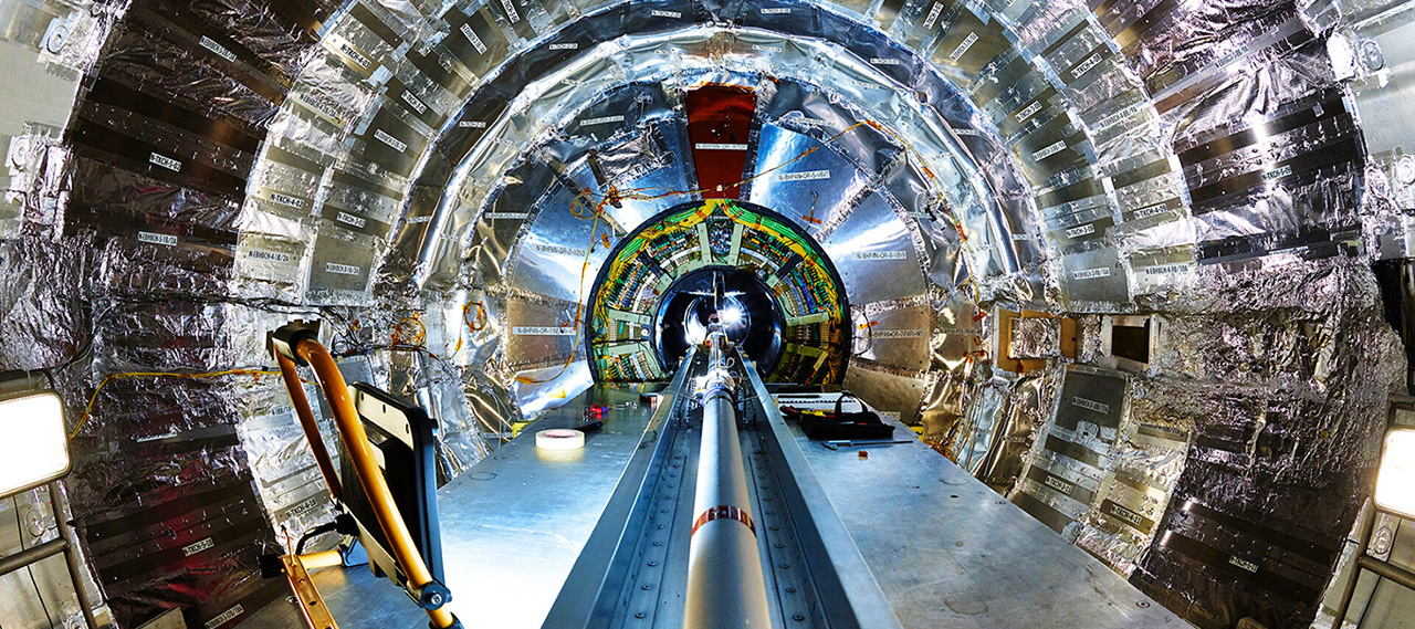 The inside of the CMS detector at CERN, showing a large central beam pipe surrounded by a silver cylinder of detectors.